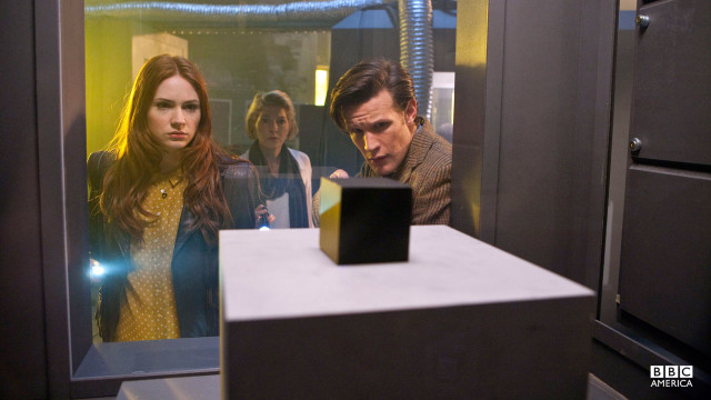 The Doctor examines a cube.