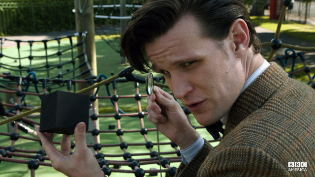 The Doctor examines a cube.