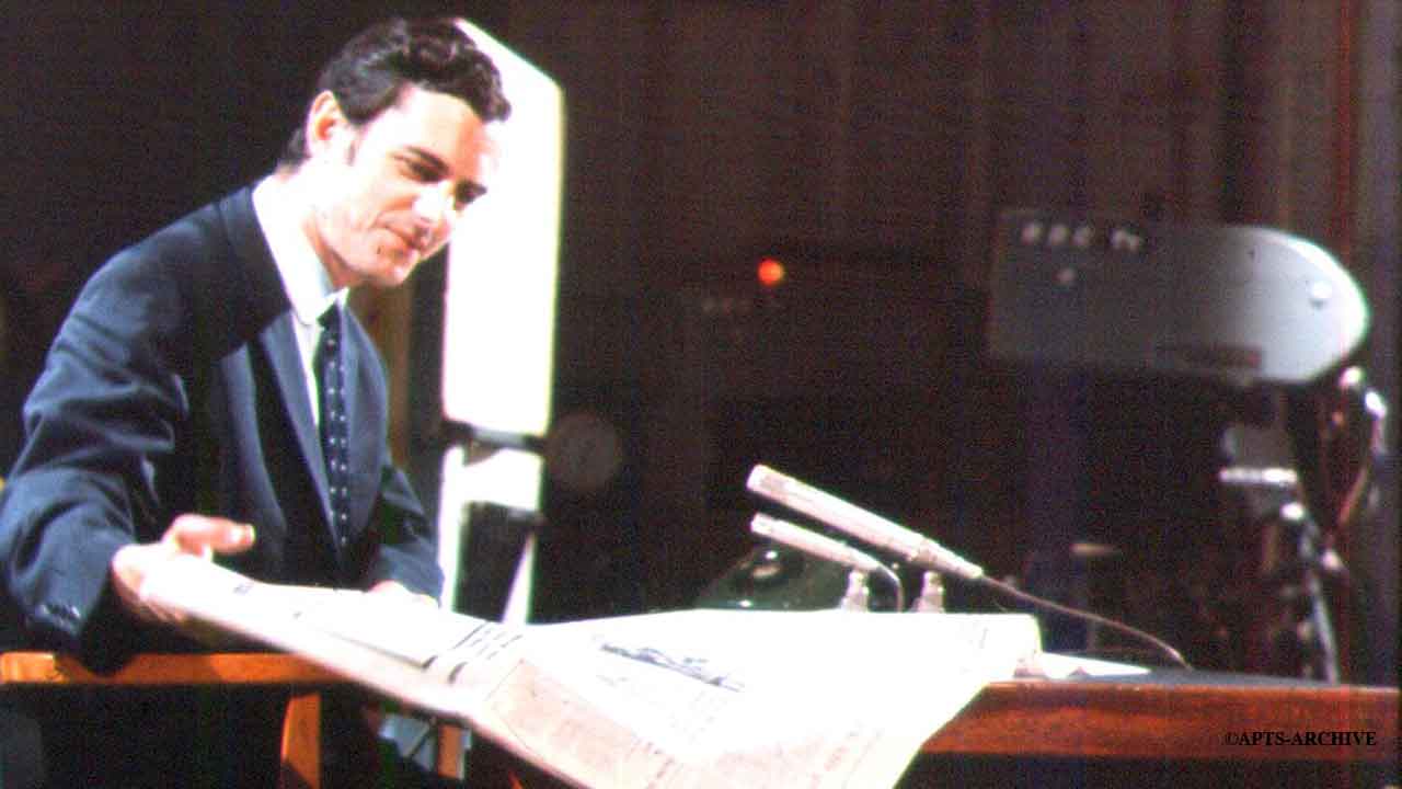 Photograph circa 1968. News reader John Edmunds (who read the news from on BBC Television from September 1968 until September 1973), sitting at the news readers desk in Studio B at Alexandra Palace. A remotely controlled television camera can be seen in the background. Four of these cameras were brought into operation at Alexandra Palace on 10th June 1961.