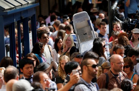 A member of the media carries a ladder through the crowd across from St Mary's Hospital Lindo Wing. (AP Photo/Sang Tan)
