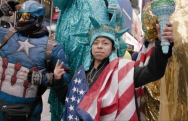 People in costumes - one with a Statue of Liberty crown and American flag.
