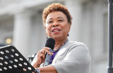 Barbara Lee, an African American woman, speaking at a podium with a microphone.