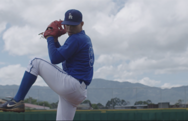 Baseball player poised to pitch the ball outside on a cloudy day.