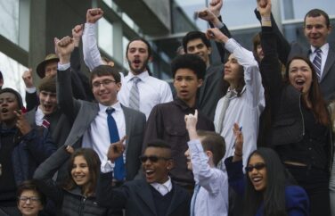 A group of teenagers cheering on steps.